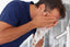 Man cleansing face at sink as part of morning and night skincare routine