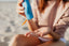 Woman squeezing sunscreen cream into her palm to reapply SPF at the beach